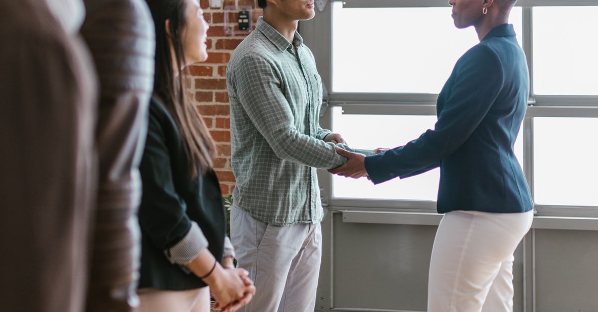 smiling business owner shaking hands with a professional service provider in a workshop setting vietnamese people