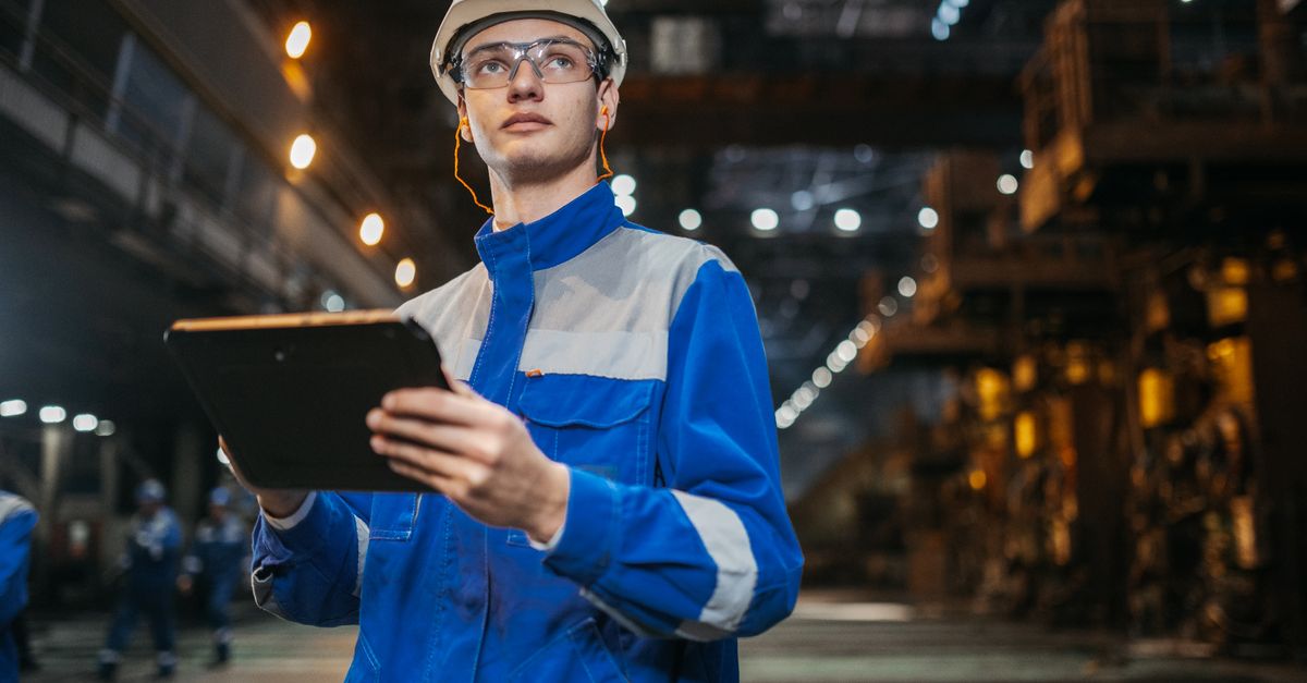 modern factory worker contacting service tablet industrial machinery background